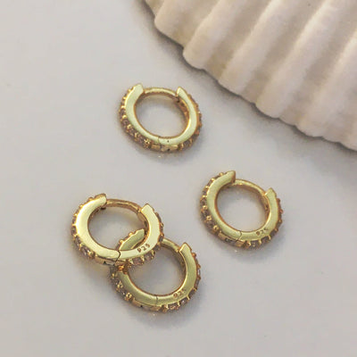 Gold Huggie earrings with Clear Zirconia gemstones.